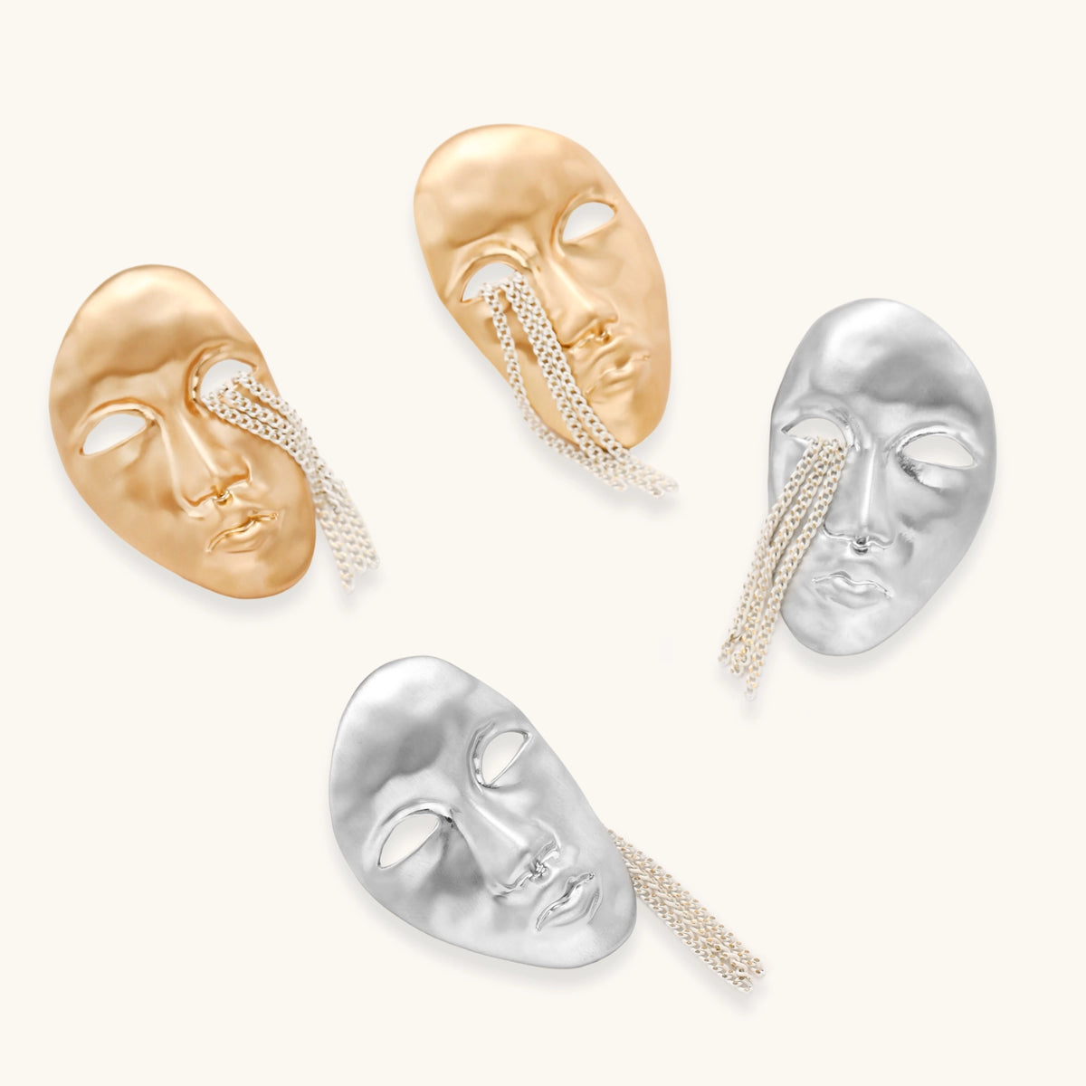 Gold-toned abstract face earrings with hollow eyes and chain details on white background, artistic statement jewelry