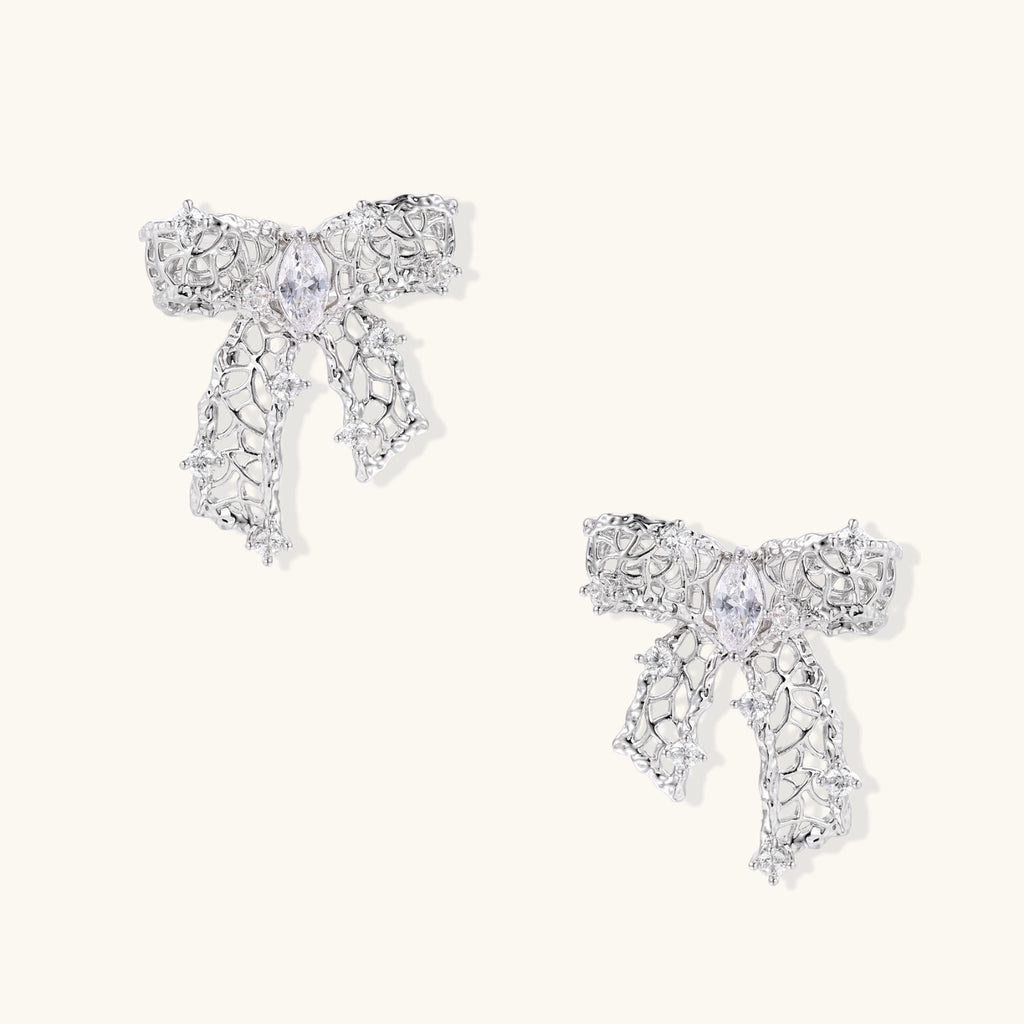 Pair of silver filigree bow-shaped stud earrings with marquise zirconia center stones and star-set crystal accents.